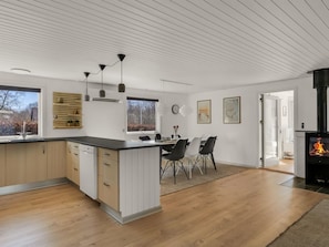 A modern kitchen with a central island, dining area with chairs, a fireplace, and large windows. - "Diuri" - 30km from the sea by Interhome (Toftlund)