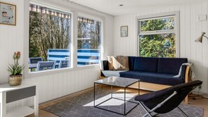 Una habitación con un sofá azul, una mesita, una silla y una lámpara.