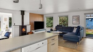 Una cocina moderna con lavavajillas Bosch, televisor integrado y estufa a leña.