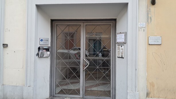 Entrada de um edifício com portão de metal, caixa de correio e placa indicando clínica médica.
