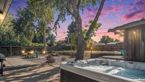 Ein Garten mit Whirlpool, Terrassenmöbeln und einem Holzzaun.