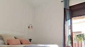 Un dormitorio con cama, ventilador de techo, ventana con cortinas y suelo de madera.