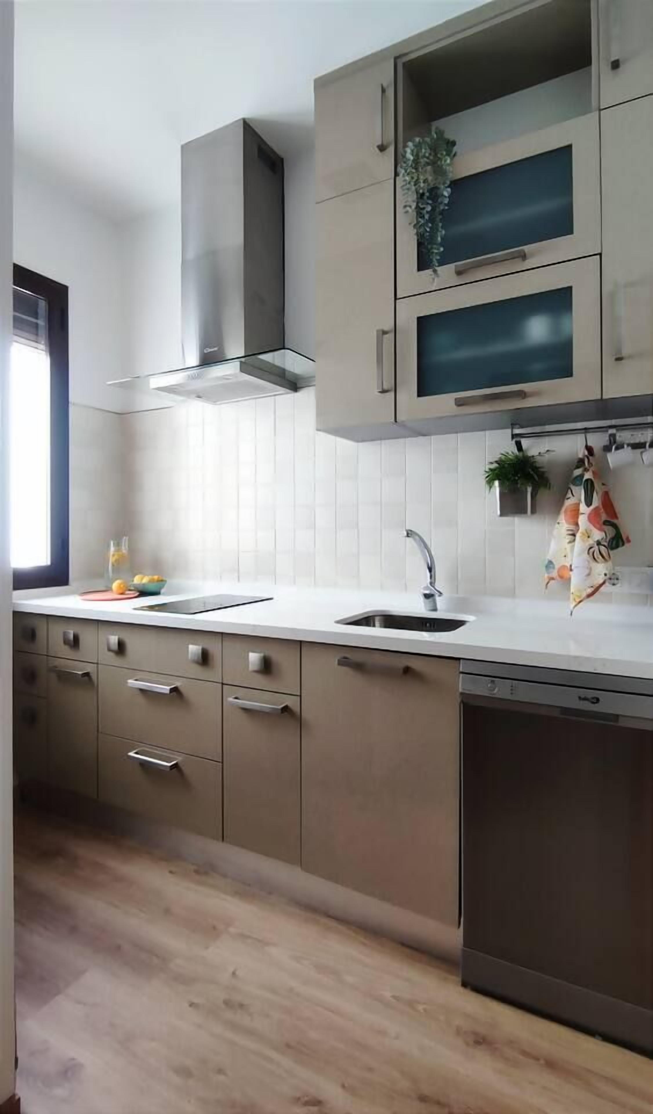 A modern kitchen with a stainless steel range hood, a double sink, and wooden cabinets.
