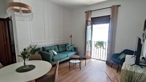Una sala de estar con un sofá verde, una mesa de comedor redonda y una silla azul.