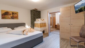 Une chambre d’hôtel moderne dotée d’un grand lit, d’un téléviseur à écran plat, d’une armoire en bois et d’une petite salle de bain visible à travers une porte ouverte.