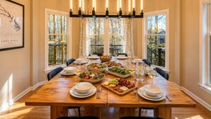 A dining room with a wooden table set for a meal, large windows, and a chandelier. - Luxurious 8-Bed Lakefront Retreat with Private Beach, Hot Tub & Sauna! (Bumpass)