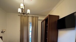 Een hotelkamer met twee bedden, een bureau, een stoel, een televisie en een kledingkast.