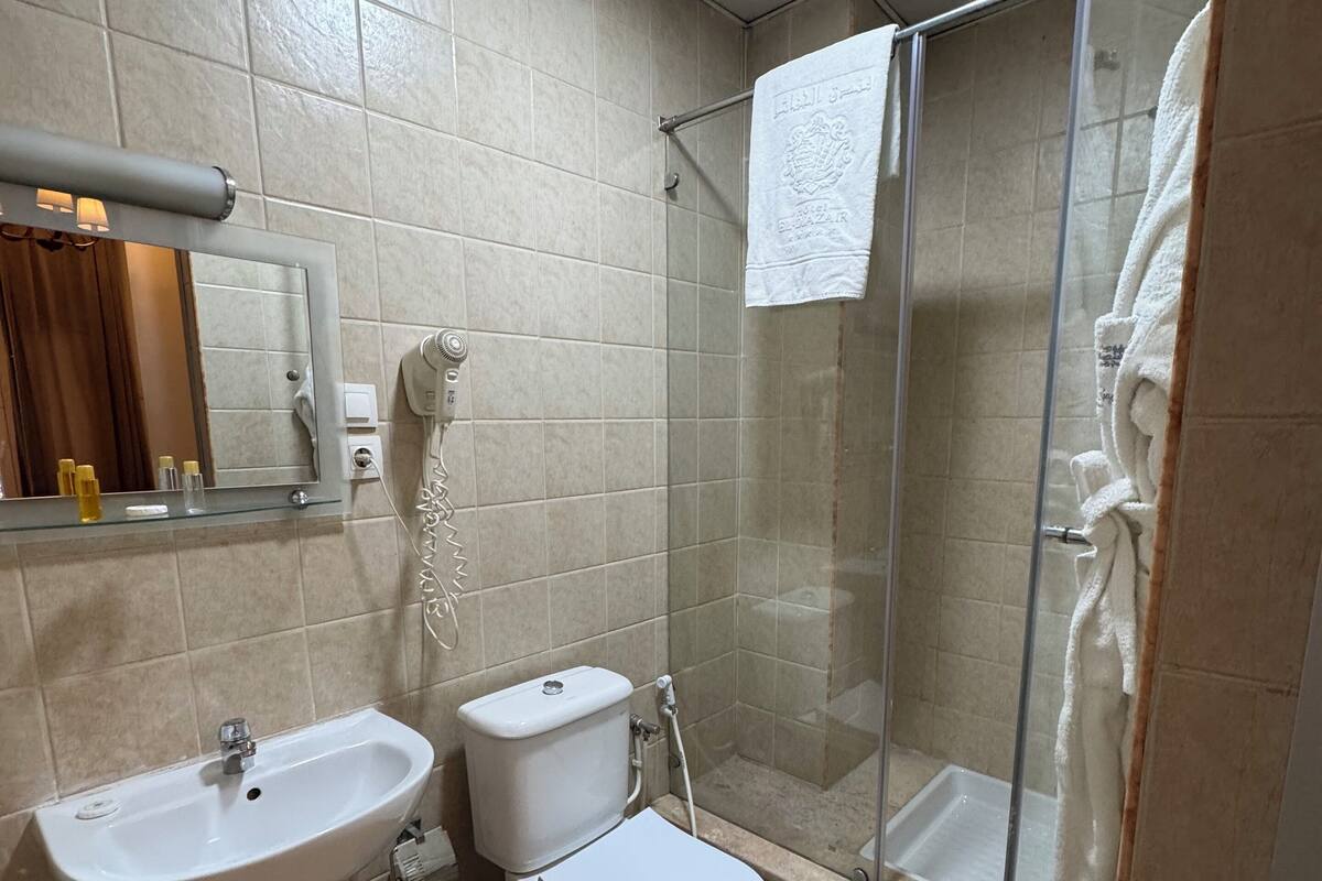 A bathroom with a sink, toilet, and glass shower enclosure.