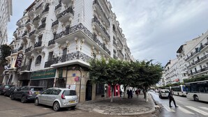 Een meerlaags gebouw met versierde balkons en een winkel op de begane grond.