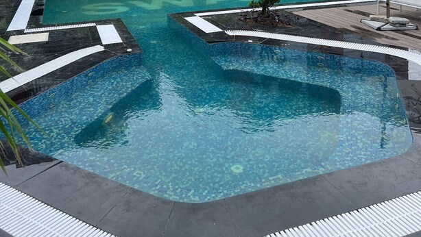 A modern building with large windows and a swimming pool with tiled edges. - FULLY FURNISHED STUDIO APARTMENT WITH   BALCONY,  (Vadodara)