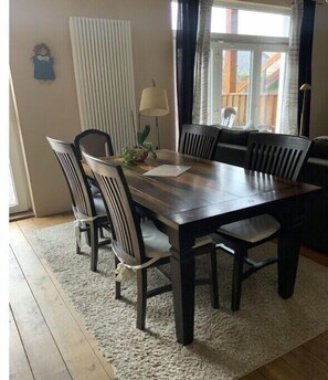 Enjoy meals in this cozy dining area with a large window, a wooden table, and six comfortable chairs.