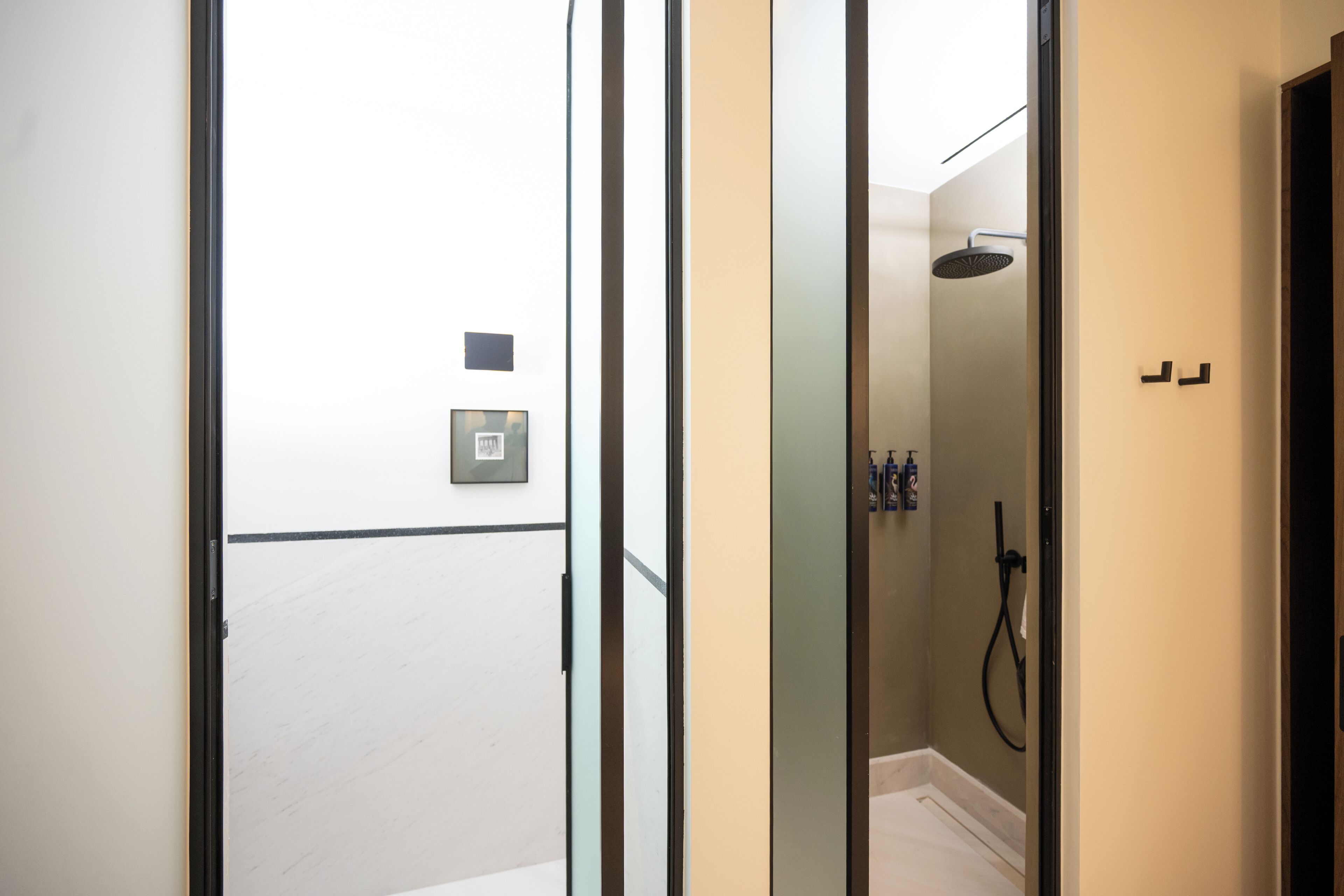 Un baño moderno con cabina de ducha de vidrio, un perchero y un calentador de agua a la vista.