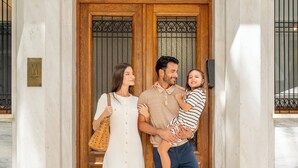 A family of three at the entrance of a building with a marble floor and a wooden door. - Athens Capital Suites-Mgallery Collection (Athens)