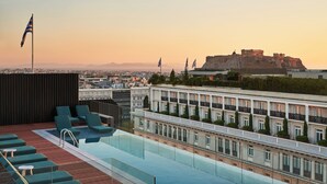 A rooftop pool with lounge chairs and a view of a historic building in the background. - Athens Capital Suites-Mgallery Collection (Athens)