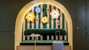 Una habitación con un sofá verde, una mesita y una maleta.