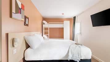 Habitación de hotel con literas, una mesita de noche con lámpara, un televisor montado en la pared y un cuadro.