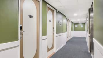 Um corredor com portas numeradas 119 e 120, piso coberto de carpete e paredes verdes.
