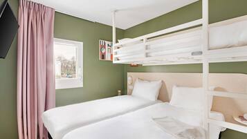 Una habitación con literas, una ventana con cortinas, un televisor de pantalla plana y una mesita.