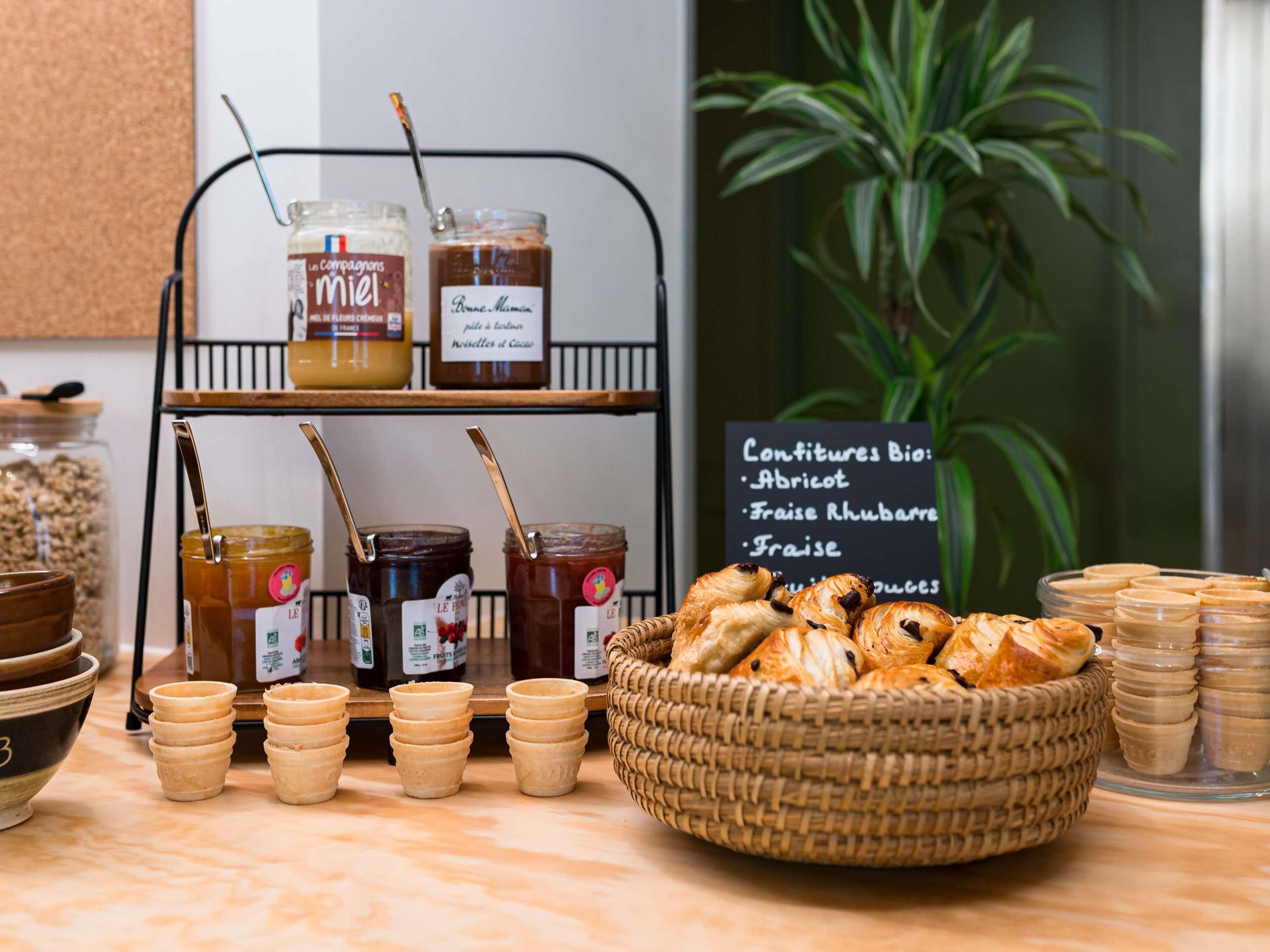 Una presentación de alimentos que incluye frascos de conservas, tazas pequeñas y una cesta de pasteles.