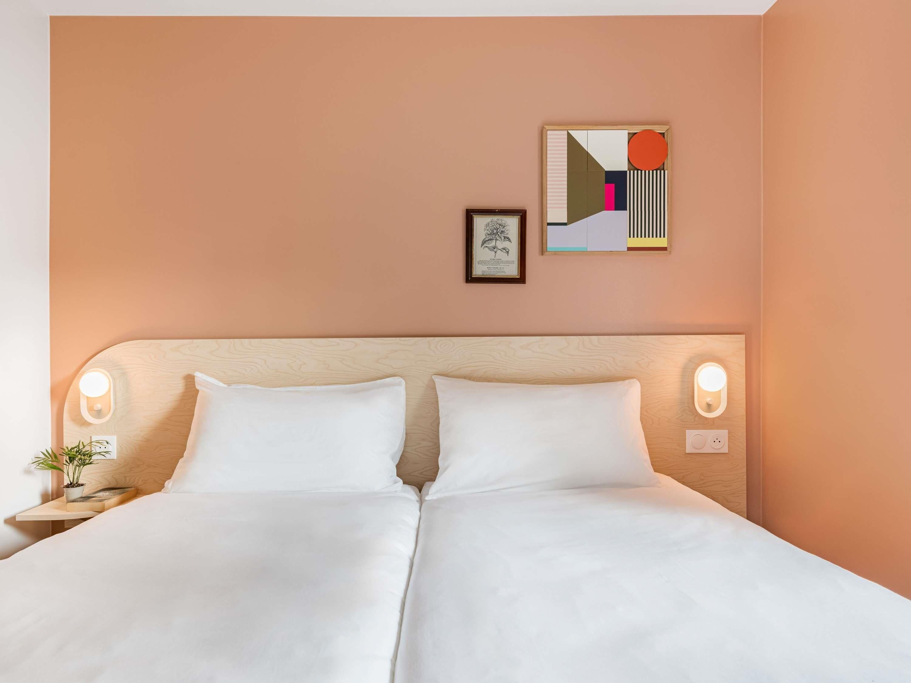 Un letto matrimoniale con due cuscini, un comodino con una lampada, un quadro incorniciato e un'opera d'arte a parete.