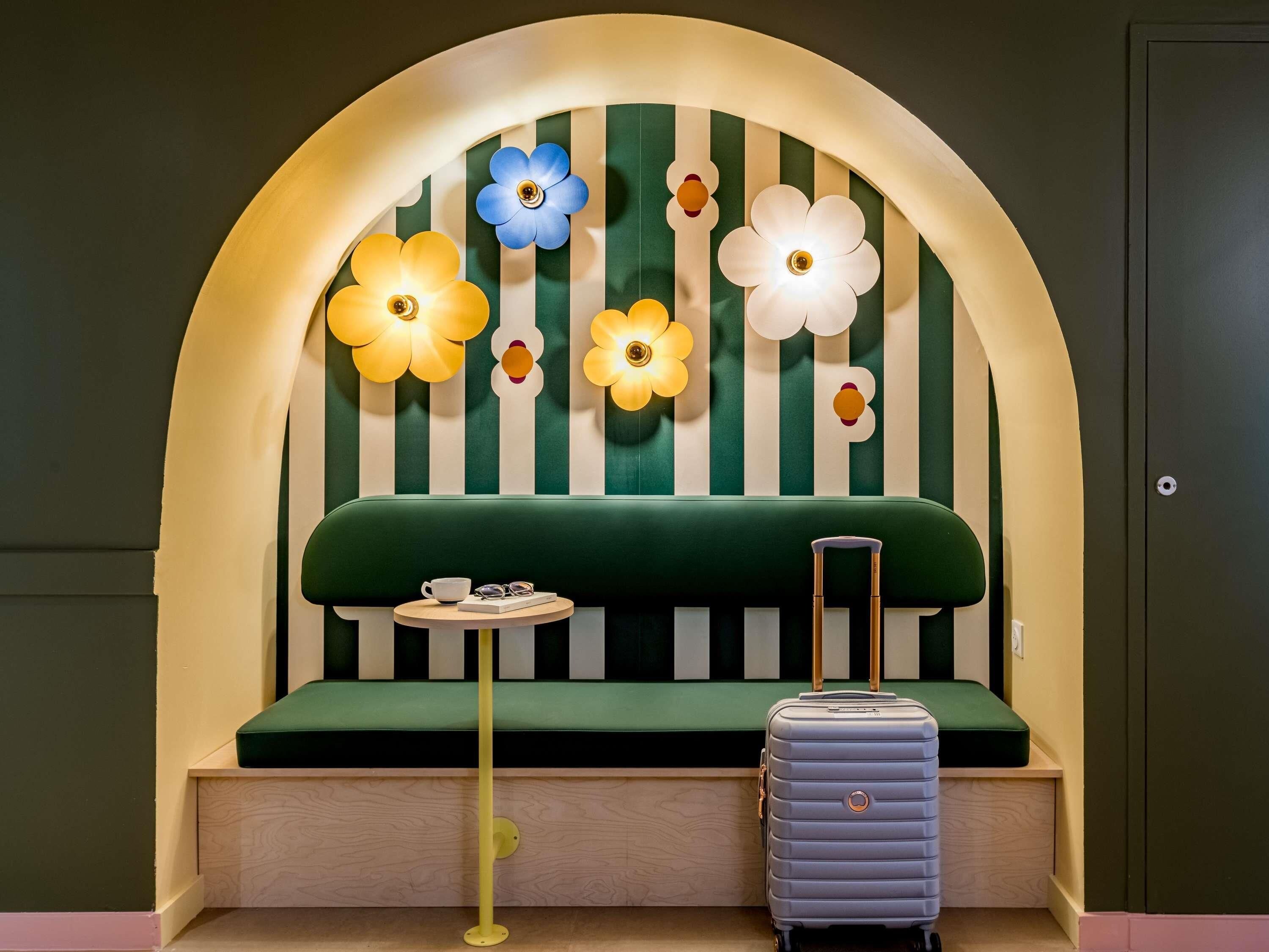 A room with a green sofa, a small round table, and a suitcase.