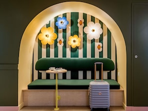 Una habitación con un sofá verde, una mesita redonda y una maleta.