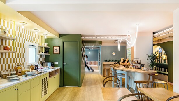 Una cocina moderna con encimera de madera, una zona de comedor con barra y una puerta verde que da a otra habitación.