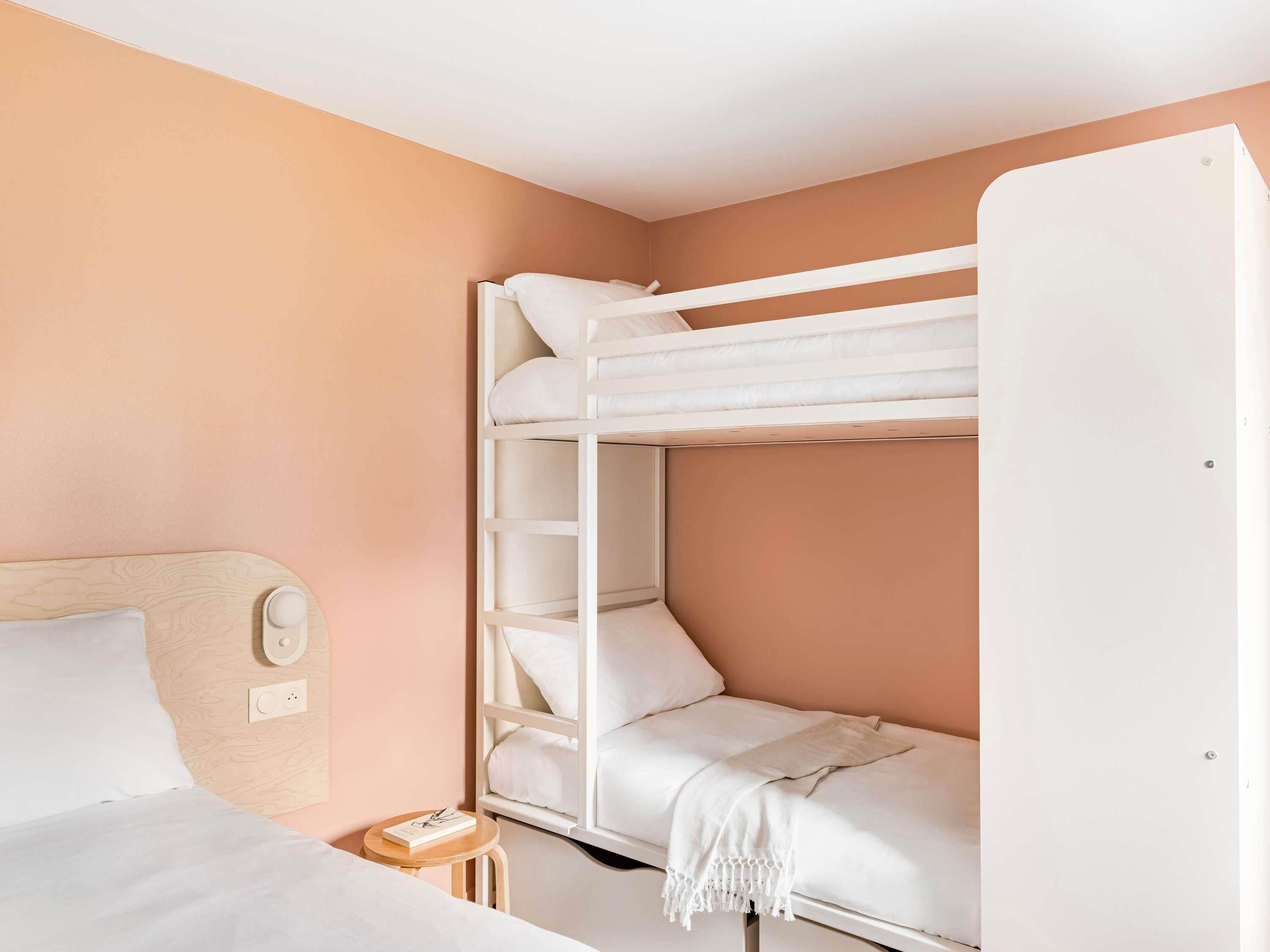 A bunk bed room with a wooden headboard, a bedside table with a book, and a white door.