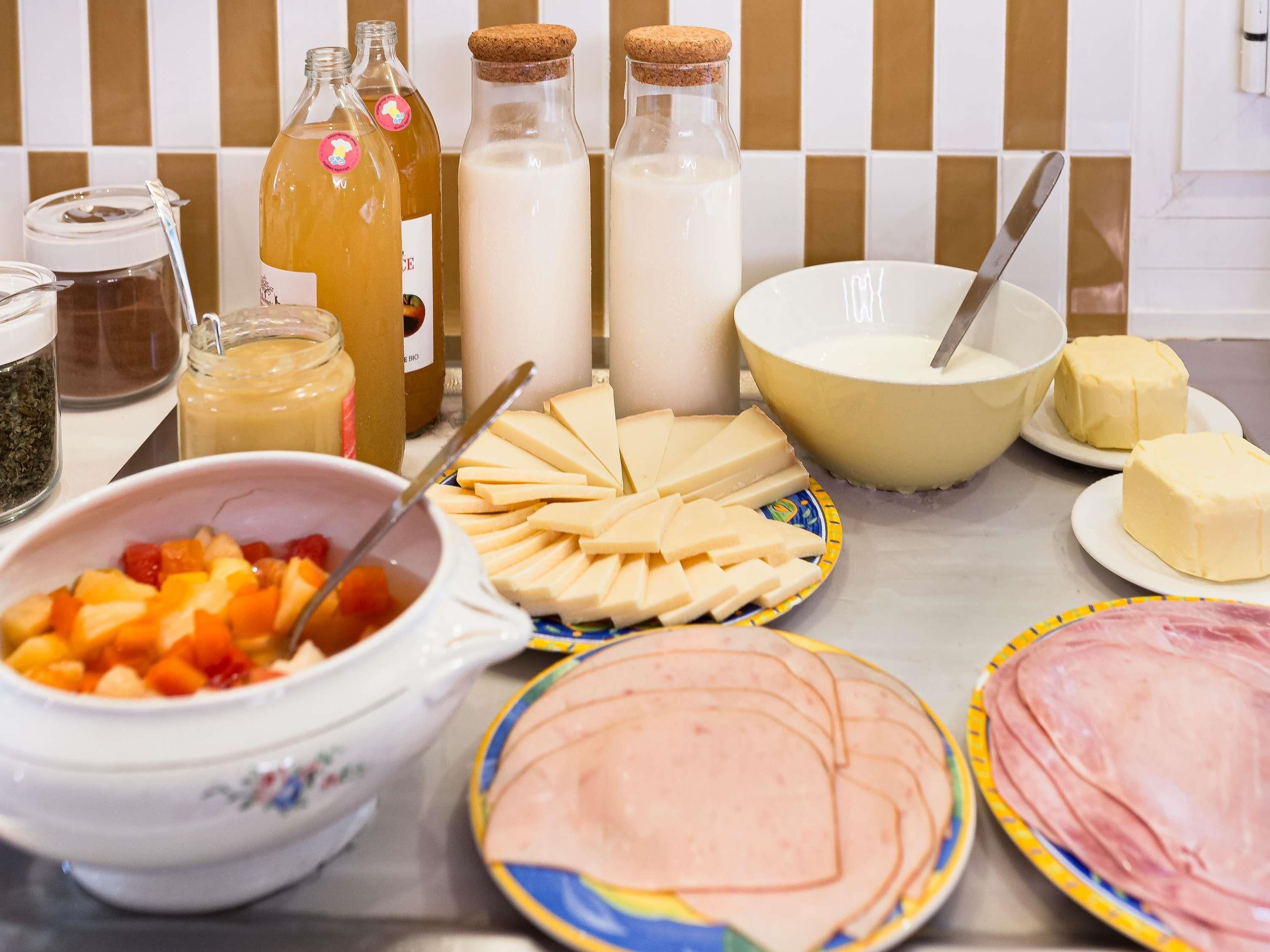 Una mesa con diversos alimentos, incluyendo queso, mantequilla y un bol de fruta.