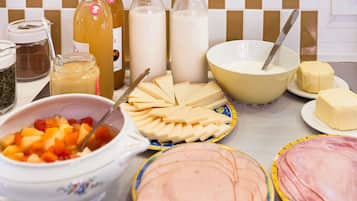 Una mesa con diversos alimentos, incluyendo queso, mantequilla y un bol de fruta.