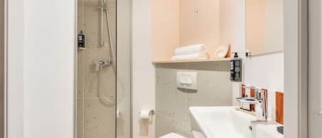 A modern bathroom with a glass-enclosed shower, a white sink, and a toilet.