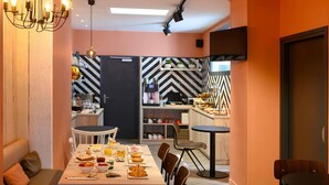 A modern kitchen with a dining area, featuring a black and white patterned backsplash, a coffee machine, and a television mounted on the wall. - Ibis Paris Tour Montparnasse 15Ème (Paris)