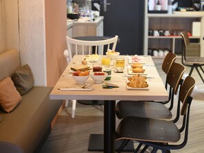 A breakfast setting with a table, chairs, and various food items. - Ibis Paris Tour Montparnasse 15Ème (Paris)