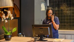Una receptionist alla scrivania con un computer, un telefono e una pianta.