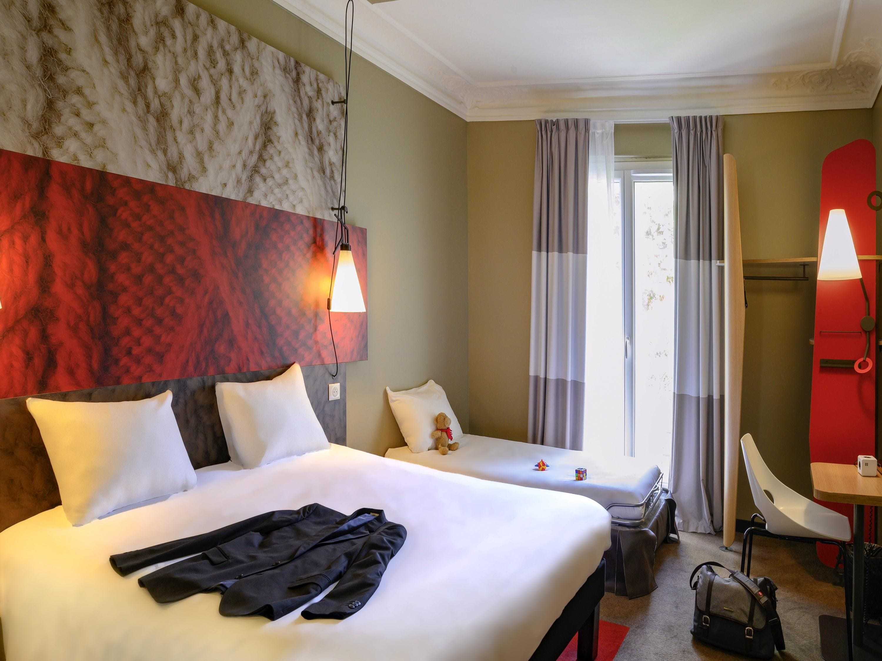 Ein Hotelzimmer mit zwei Betten, einem Schreibtisch und einem Stuhl.