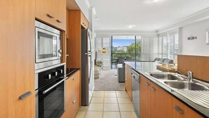 Una cucina moderna con mobili in legno, elettrodomestici in acciaio inossidabile e vista all'esterno.
