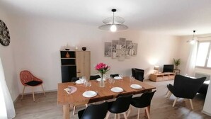 A dining area with a wooden table set for four, surrounded by black chairs. There is a vase with pink flowers on the table. - Josephine's House with swimming pool (Pierrelatte)
