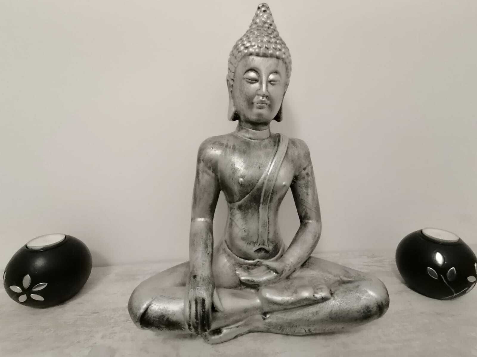 Eine sitzende Statue mit spitzer Spitze, auf einer ebenen Fläche platziert, mit zwei kugelförmigen Objekten an jeder Seite.