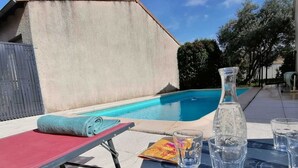 A poolside area with a lounge chair, a table with glasses and a bottle, and a pool in the background. - Josephine's House with swimming pool (Pierrelatte)