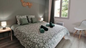 A bedroom with a large bed, two bedside tables, a window with curtains, and a hanging light fixture. - Josephine's House with swimming pool (Pierrelatte)