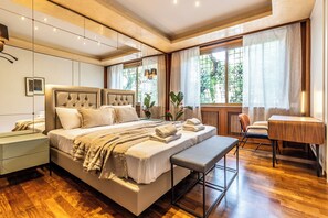 A modern bedroom with a large bed, bedside tables, a bench, and a desk. - Vatican SPA and Sauna Flatinrome (Rome)