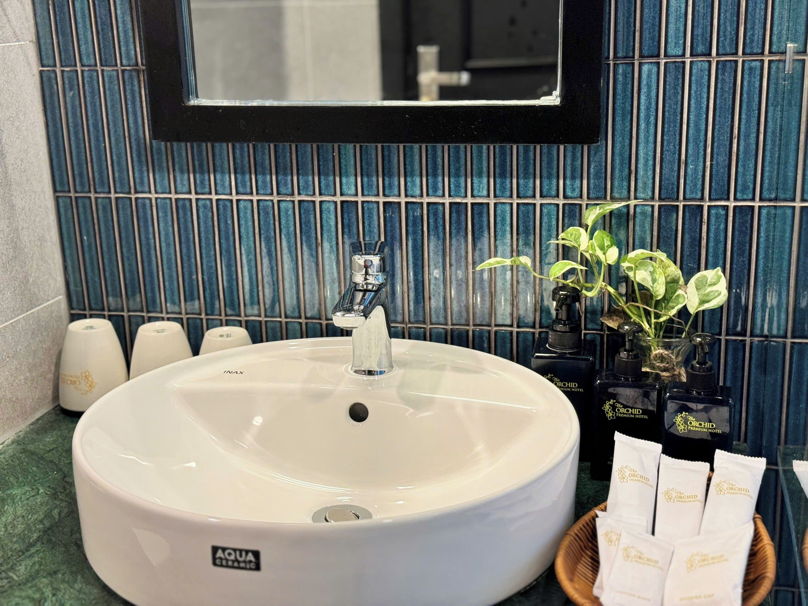 A bathroom with a white ceramic sink, a mirror above it, and a blue tiled wall.