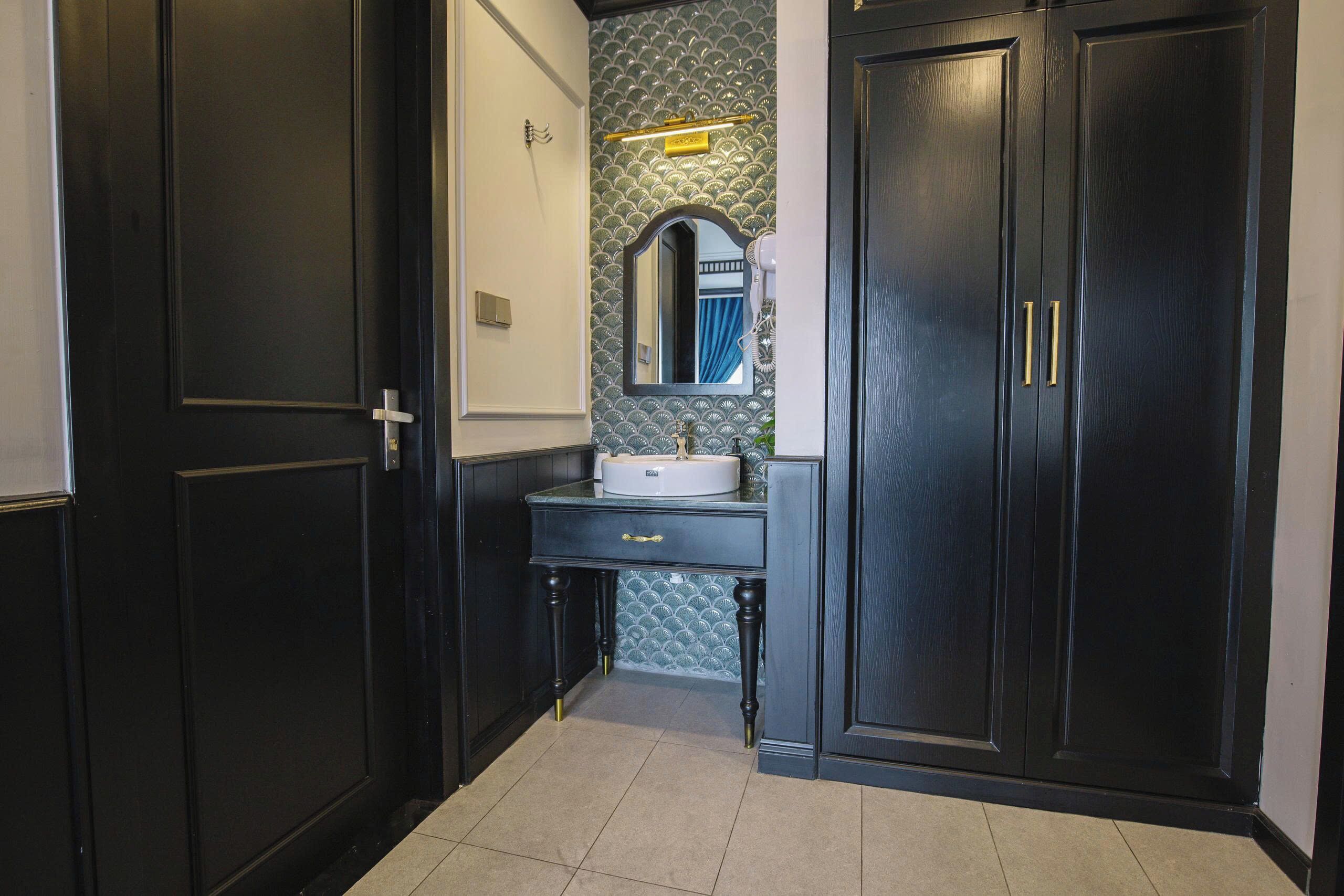 A bathroom with dark wood cabinetry, a white sink, and a mirror with a blue curtain.