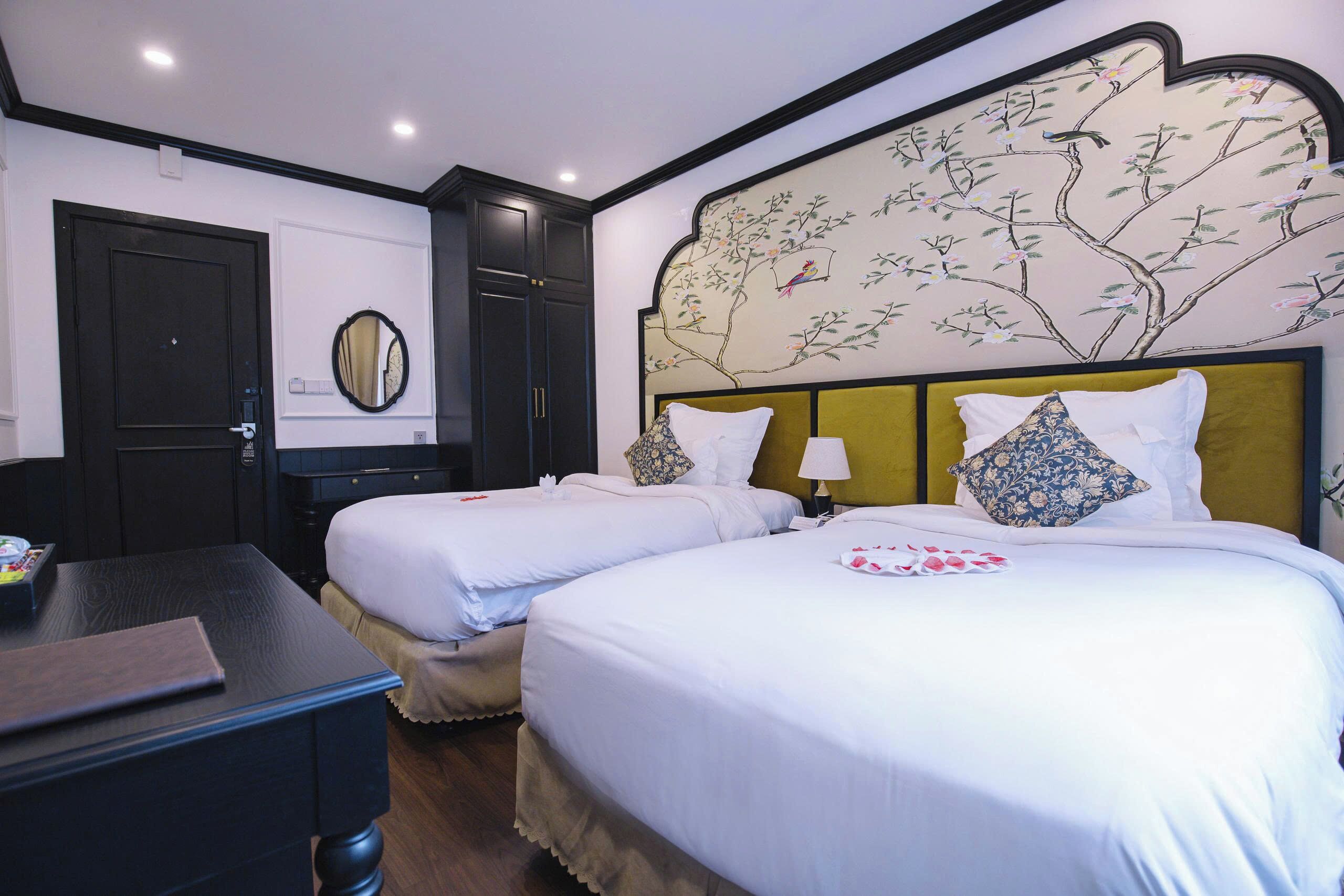 A hotel room with two beds, a desk, and a wall-mounted mirror.