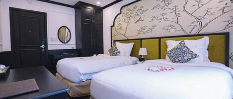 A hotel room with two beds, a desk, and a wall-mounted mirror.
