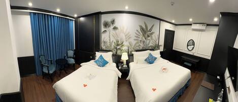 A hotel room with two beds, a desk, a chair, a TV, and a wall with a tropical mural.