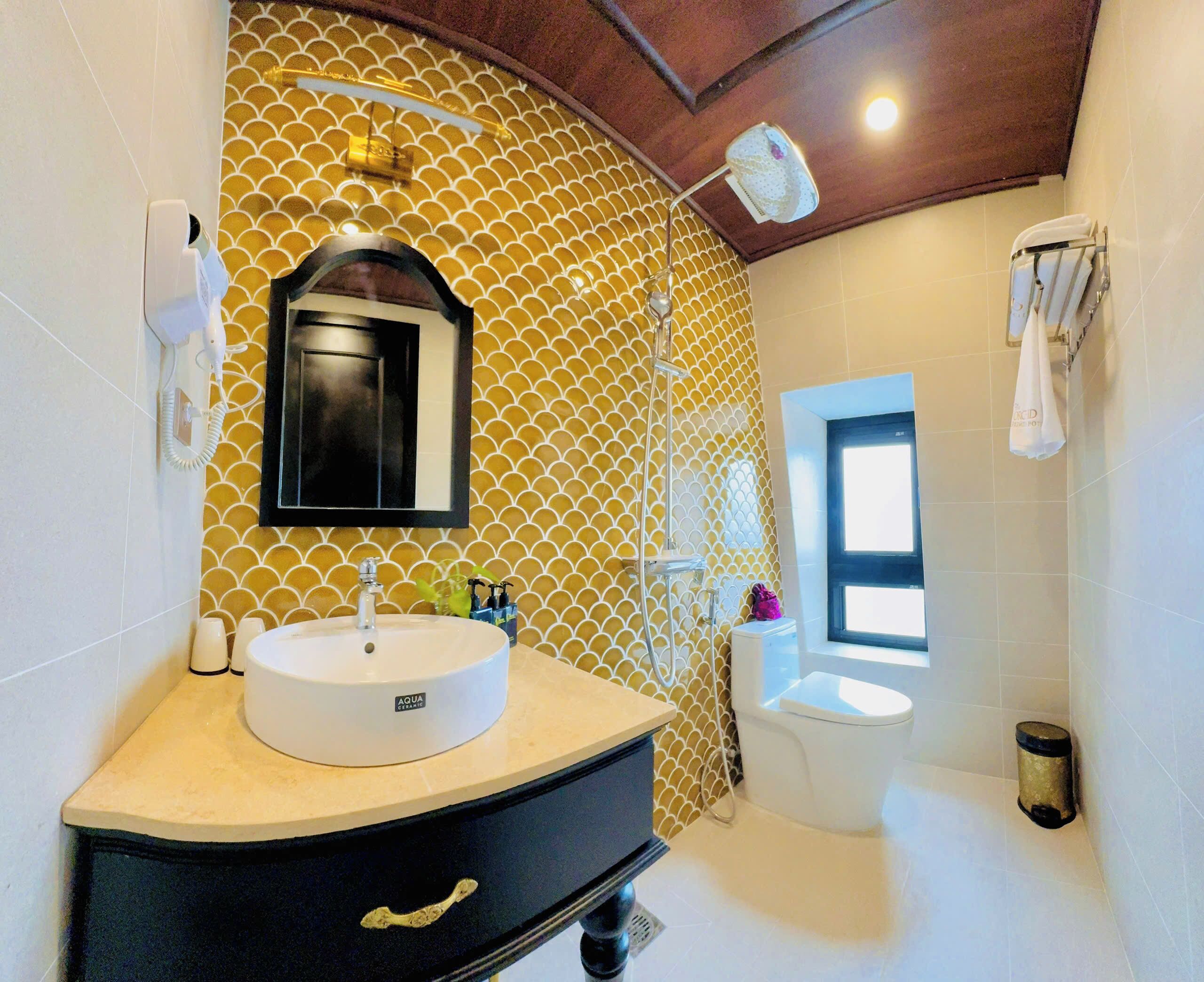 A bathroom with a round sink, a mirror, a toilet, and a shower.
