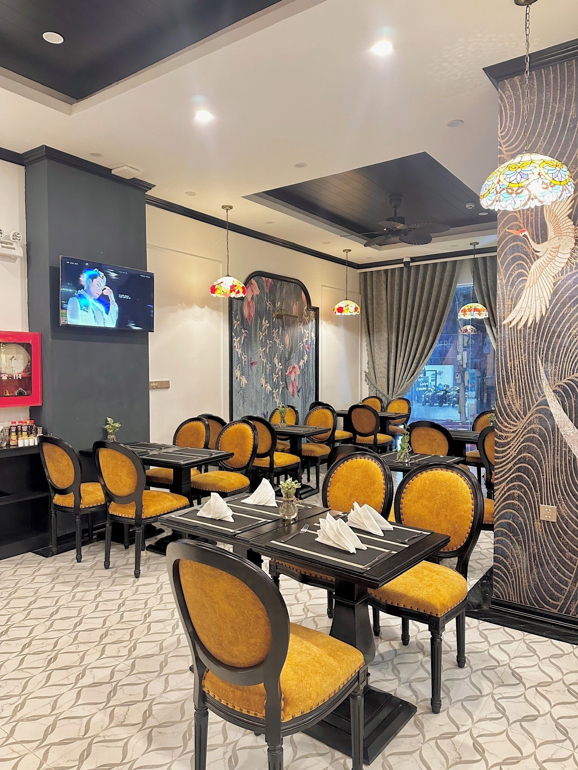 A restaurant interior with tables and chairs, a TV screen, and decorative elements.