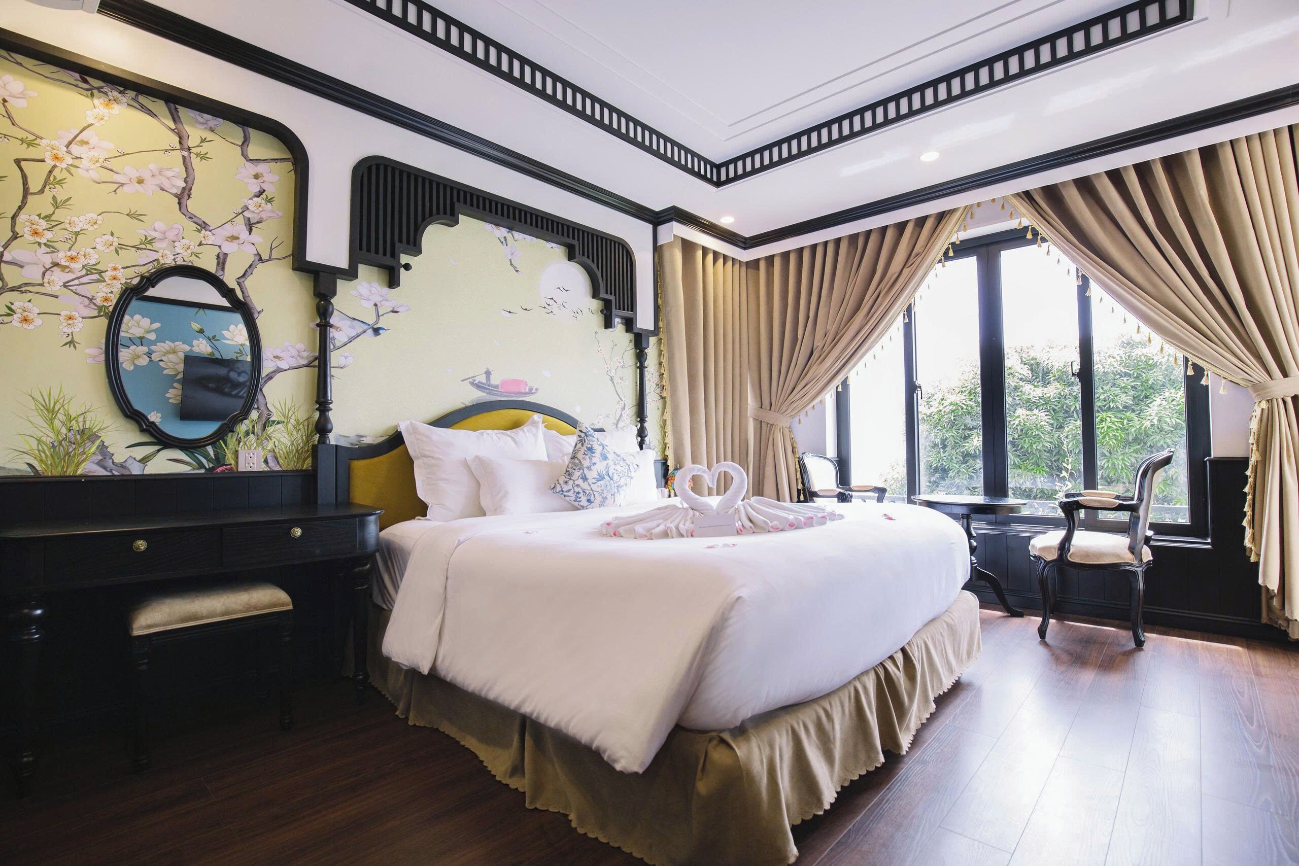A large bed with a white comforter, a bedside table, a mirror, and a window with curtains.