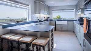 Una cucina moderna con una grande isola, sgabelli da bar e vista sul paesaggio.